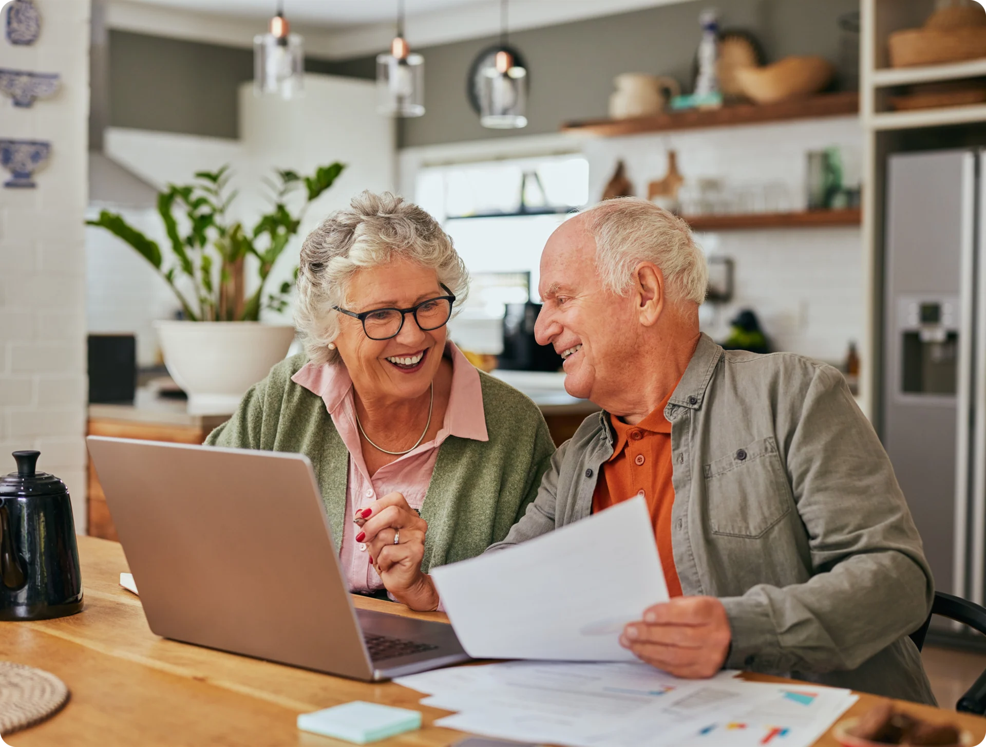 Elderly couple smiling while using a laptop.