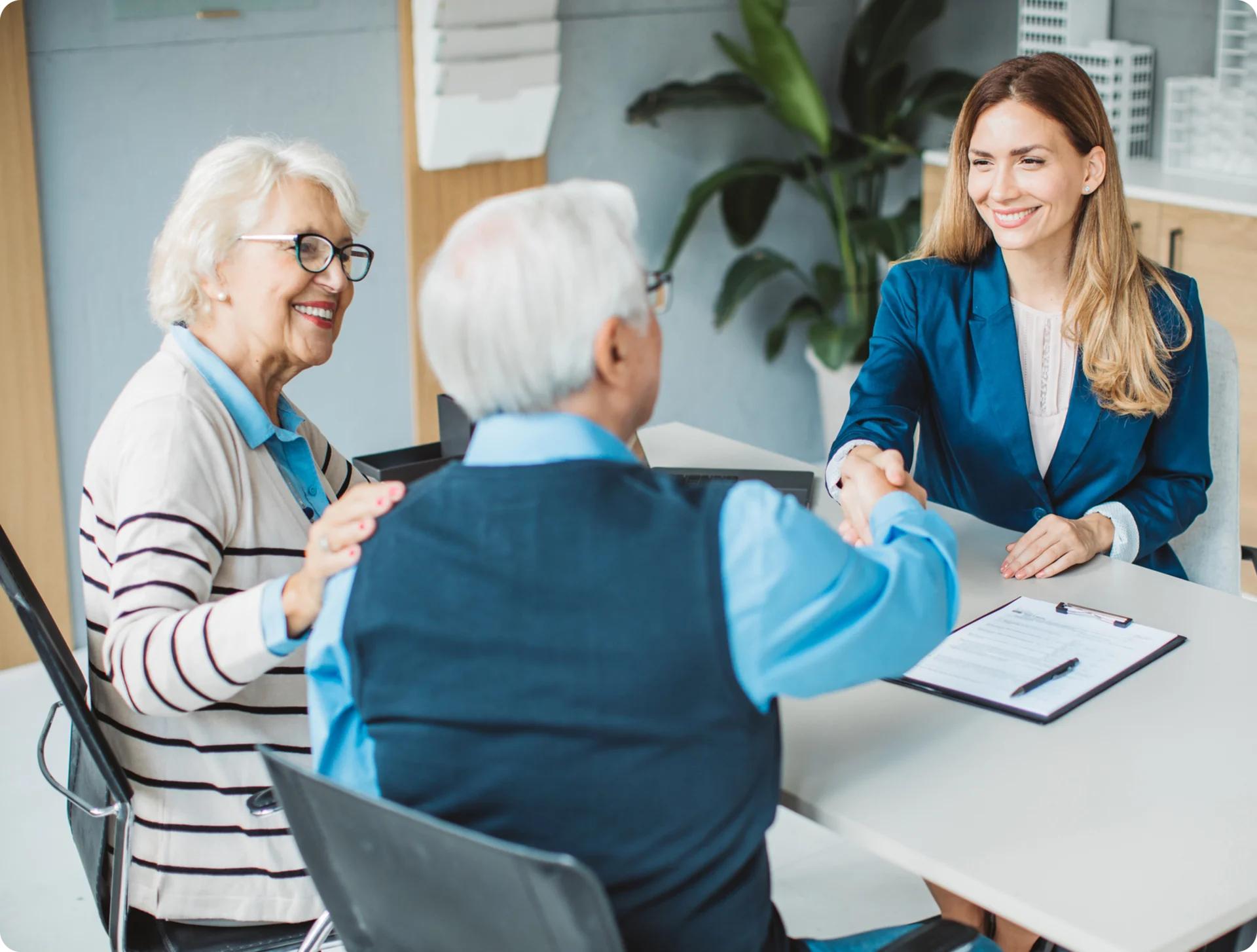 Elderly couple shaking hands with advisor.