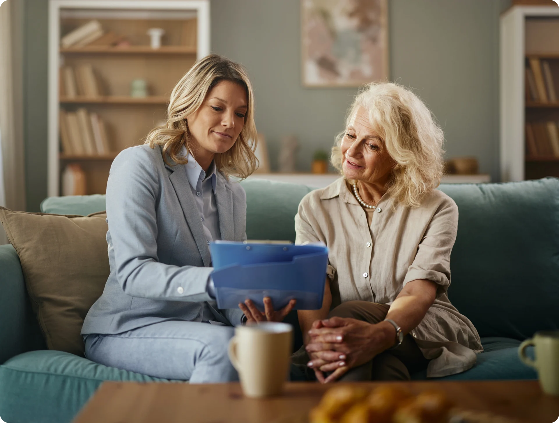 Two women discussing documents on a couch.