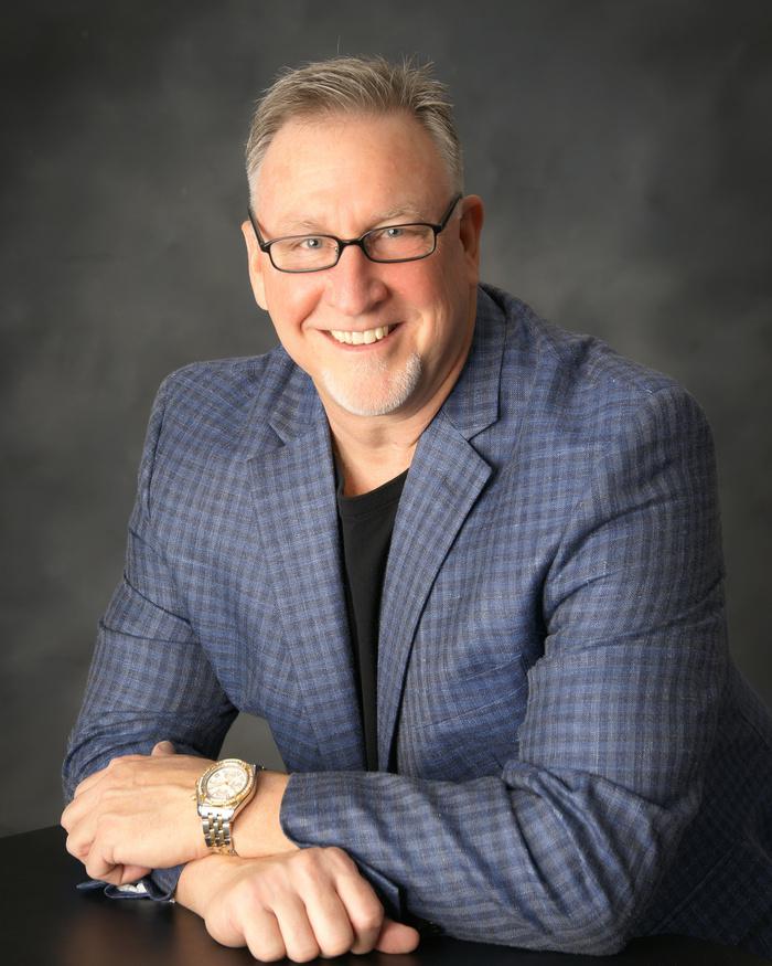 Smiling man in glasses and blue blazer.